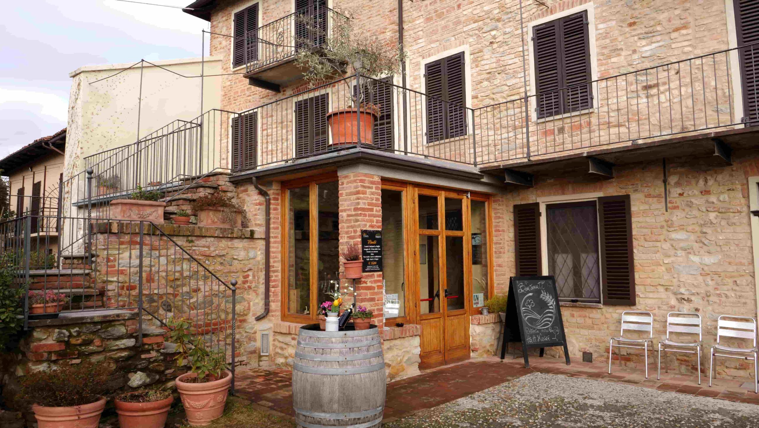 Ingresso dell'Osteria della Pompa a Cocconato con botte e lavagna del menu
